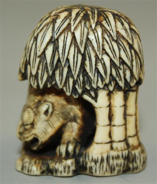 A Japanese stained ivory netsuke of a tiger crouching beneath a tree, 18th / 19th century, 4.2cm.